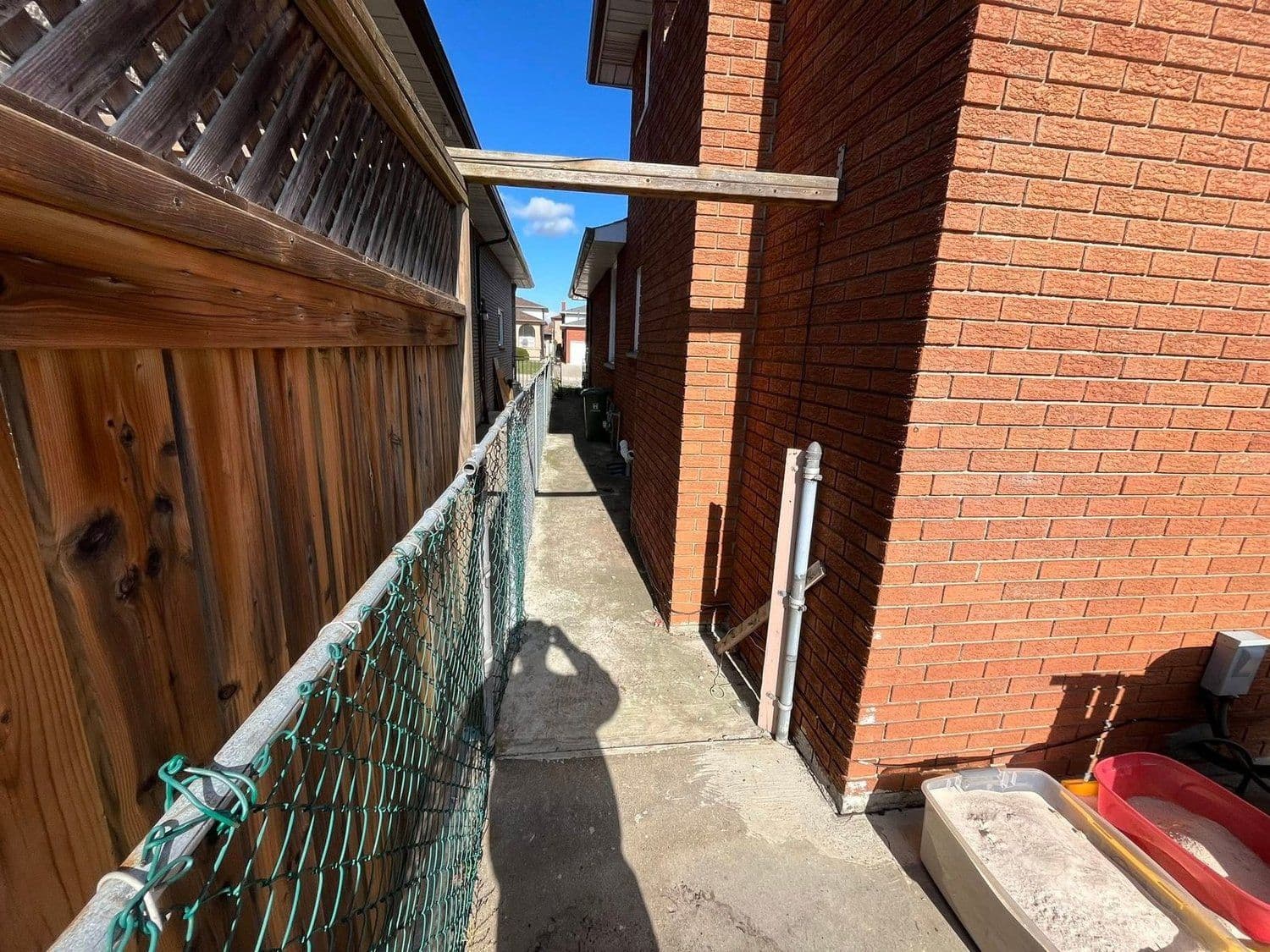 Freshly pressure-washed concrete walkway between a home and fence