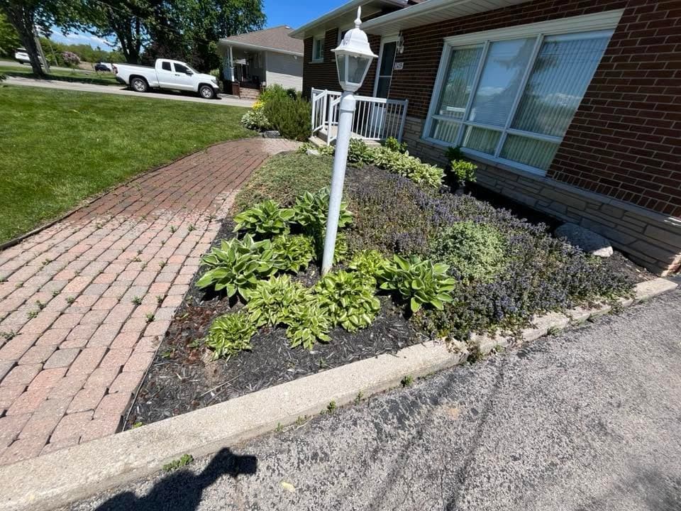 Interlock brick walkway and fresh garden bed leading to a home