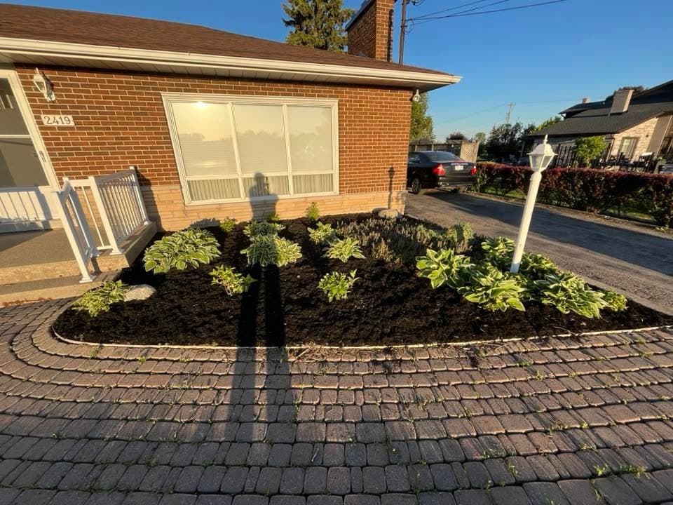 Fresh black mulch garden bed curving along a brick home